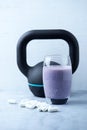 Glass of Protein Shake with milk and blueberries. Creatine capsules and black sporting kettlebell in background. Sport nutrition. Royalty Free Stock Photo