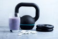 Glass of Protein Shake with milk and blueberries. Creatine capsules, black sporting kettlebell and plates in background. Sport nut Royalty Free Stock Photo