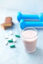 Glass of protein shake with milk and raspberries. protein bar, BCAA amino acids, L - Carnitine capsules and blue dumbbells in back Royalty Free Stock Photo