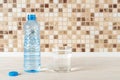 Glass of pure drinking water and half full blue plastic bottle on a white wood table. Quench thirst and health care concept. Copy Royalty Free Stock Photo