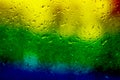 Glass with rain drops in rainbow colors. Raindrops on window closeup Royalty Free Stock Photo