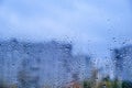 Glass with raindrops on the background of a blurred city. Autumn window with the texture of water drops against a cloudy gray sky Royalty Free Stock Photo