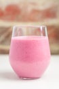 Glass of raspberry and banana smoothie on a white table Royalty Free Stock Photo