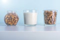 Glass of raw almonds, vegetable milk and jar with soaking nuts. Concept of making plant based organic veggie Milk, lactose free