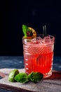 Glass of red alcoholic cocktail drink with ice, mint and lime. Summer refreshing drink Royalty Free Stock Photo