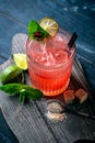 Glass of red alcoholic cocktail drink with ice, mint and lime. Summer refreshing drink Royalty Free Stock Photo