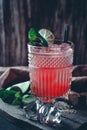 Glass of red alcoholic cocktail drink with ice, mint and lime. Summer refreshing drink Royalty Free Stock Photo