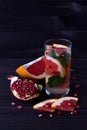 Glass of red cocktail with slices of ripe grapefruit and pomegranate on black background. detox water. diet healthy eating and wei Royalty Free Stock Photo