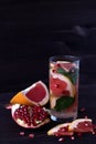 glass of red cocktail with slices of ripe grapefruit and pomegranate on black background. detox water. diet healthy eating and wei Royalty Free Stock Photo