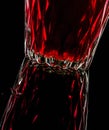 A glass with red drink on a dark background.