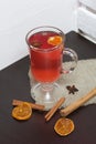 A glass of red drink stands on a piece of linen. A slice of dried orange and anise floats in it. Nearby are cinnamon sticks and Royalty Free Stock Photo