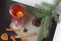 A glass of red drink stands on a piece of linen. A slice of dried orange and anise floats in it. Nearby are cinnamon sticks and Royalty Free Stock Photo