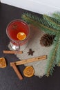 A glass of red drink stands on a piece of linen. A slice of dried orange and anise floats in it. Nearby are cinnamon sticks and Royalty Free Stock Photo