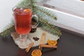 A glass of red drink stands on a piece of linen. A slice of dried orange and anise floats in it. Nearby are cinnamon sticks and Royalty Free Stock Photo