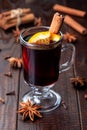 Glass of red glogg or mulled wine with orange slices and cinnamon stick on dark wooden background, vertical