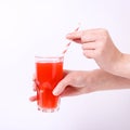 A glass with red grapefruit juice and a straw in her hand into a girl. Isolate on white background Royalty Free Stock Photo