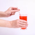 A glass with red grapefruit juice and a straw in her hand into a girl. Isolate on white background Royalty Free Stock Photo