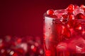 A glass of red pomegranate drink with ice cubes and red fruit pieces. pomegranate juice close up, with transparent ice, dark red Royalty Free Stock Photo