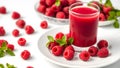 A glass of red juice is on a white plate with a bunch of raspberries Royalty Free Stock Photo