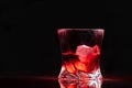 Glass of red rum on ice illuminated on black Royalty Free Stock Photo