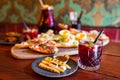 Glass of red Sangria on a table full of food with tapas platter in the background and an can of more Sangria