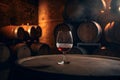 Glass of red sparkling wine on background of wooden oak barrels in cellar of winery. AI generated Royalty Free Stock Photo