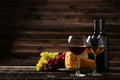 Glass of red and white wine, cheeses and grapes on the brown wooden background Royalty Free Stock Photo