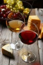 Glass of red and white wine, cheeses and grapes on grey wooden background Royalty Free Stock Photo