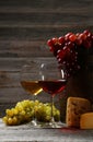 Glass of red and white wine, cheeses and grapes on the grey wooden background Royalty Free Stock Photo