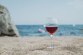 Glass of red wine against the background of the Mediterranean beach and the sea in a tourist town in the summer under Royalty Free Stock Photo