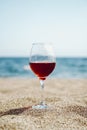 Glass of red wine against the background of the Mediterranean beach and the sea in a tourist town in the summer under Royalty Free Stock Photo