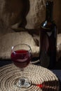 A glass of red wine on a background of burlap. Bottle of red wine.