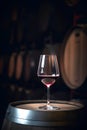 Glass of red wine on background of wooden oak barrels in cellar of winery Royalty Free Stock Photo