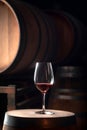 Glass of red wine on background of wooden oak barrels in cellar of winery Royalty Free Stock Photo