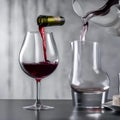 A glass of red wine being poured into a decanter, capturing the rich color1