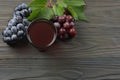 Glass of red wine with blue grapes and green leaf on dark wooden table. Top view with copy space Royalty Free Stock Photo