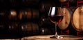 Glass of red wine with a blurred background of cellar, wine-vault with barrels. Generative AI