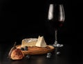 A glass and a bottle of red wine, brie cheese on a wooden plate, fresh figs and blueberries on a dark table Royalty Free Stock Photo