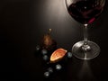 A glass and a bottle of red wine, brie cheese on a wooden plate, fresh figs and blueberries on a dark table Royalty Free Stock Photo