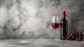 A glass of red wine, a bottle and a bunch grapes against the background of a table and a gray marble wall. Copy space. Royalty Free Stock Photo