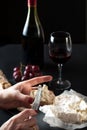 Glass of red wine with a bottle, cluster of grapes, women hand placing brie cheese to rustick piece of bread with antique knife. Royalty Free Stock Photo