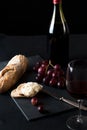 Glass of red wine with a bottle, cluster of grapes, women hand placing brie cheese to rustick piece of bread with antique knife. Royalty Free Stock Photo