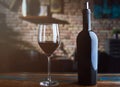 Glass of red wine and wine bottle on colorful wooden table at home Royalty Free Stock Photo