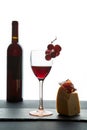 Glass of red wine beside bottle and piece of hard cheese and prosciutto on white background Royalty Free Stock Photo