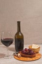 Glass of red wine, bottle, and rare wood plate with corkscrew cork, bowl of crackers Royalty Free Stock Photo