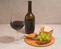 Glass of red wine, bottle, and rare wood plate with corkscrew cork, bowl of crackers Royalty Free Stock Photo