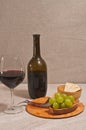 Glass of red wine, bottle, and rare wood plate with corkscrew and  of green grapes Royalty Free Stock Photo