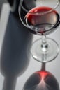 Glass of red wine and bottle with shadows and reflections on a white textured surface. Royalty Free Stock Photo