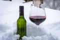 A glass of red wine and  bottle of wine in snow Royalty Free Stock Photo