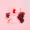 A glass of red wine a bunch of grapes corkscrew on a gentle pink background. Minimalism. Top view flat layout Royalty Free Stock Photo